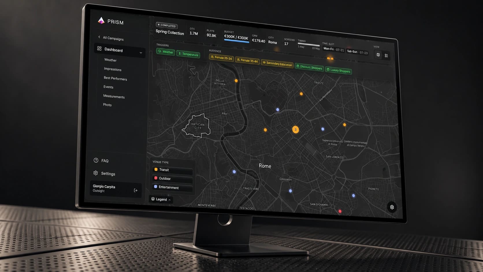 PRISM campaign dashboard and Rome map on a black desktop monitor in a dark studio.